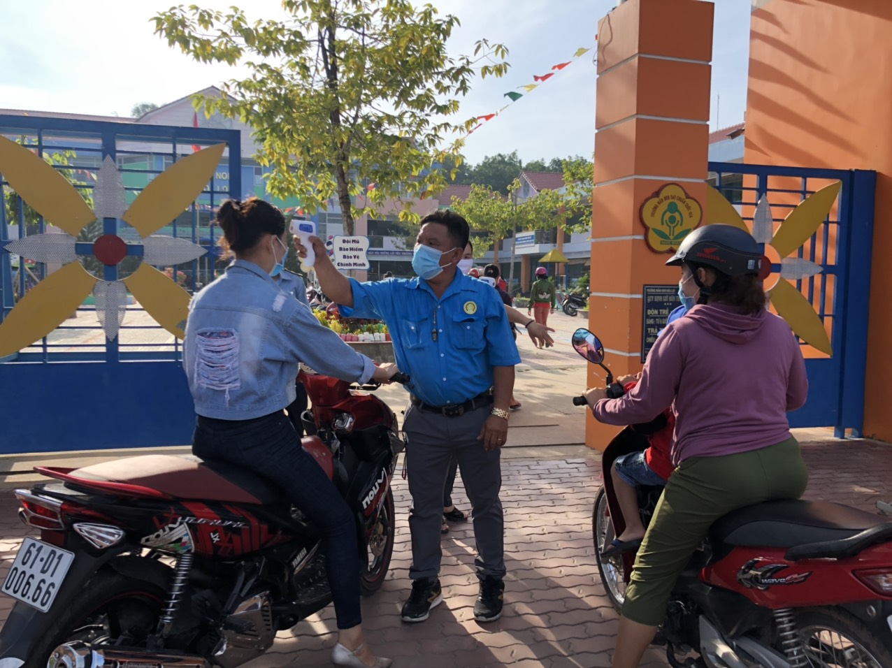 Phụ huynh được đo thân nhiệt, đeo   khẩu trang trước   khi vào trường dự họp